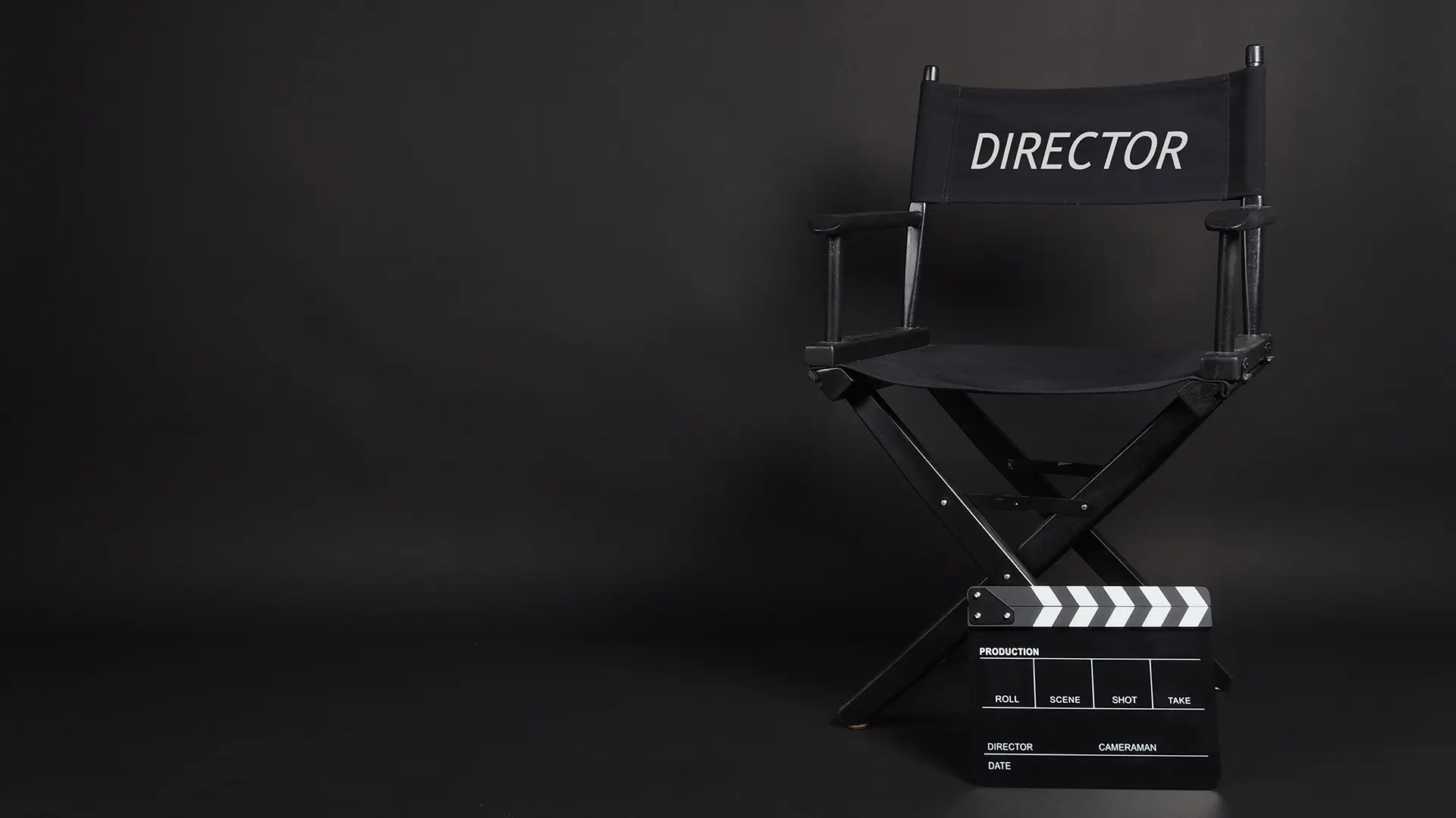 Regiestuhl und Filmklappe auf schwarzem Hintergrund.